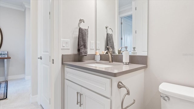 bathroom with toilet, baseboards, ornamental molding, and vanity