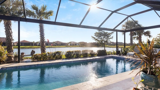 outdoor pool featuring a water view, glass enclosure, and a patio area