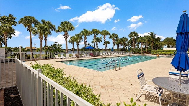 pool with a patio area and fence