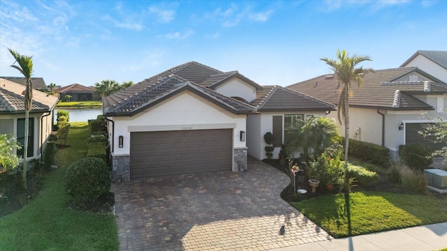 view of front facade with stone siding, decorative driveway, a tiled roof, and an attached garage