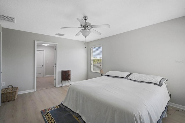 bedroom featuring light wood-style floors, baseboards, visible vents, and a ceiling fan