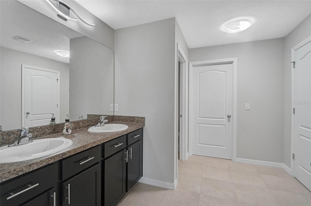 full bath featuring double vanity, tile patterned flooring, a textured ceiling, and a sink