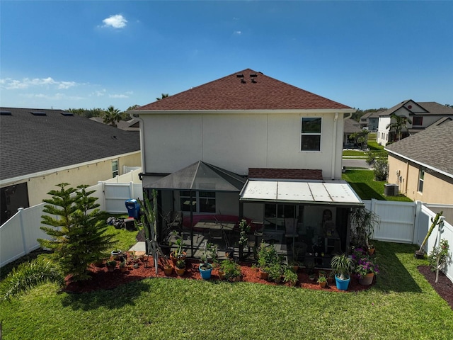 rear view of house featuring roof with shingles, a lawn, a fenced backyard, and stucco siding