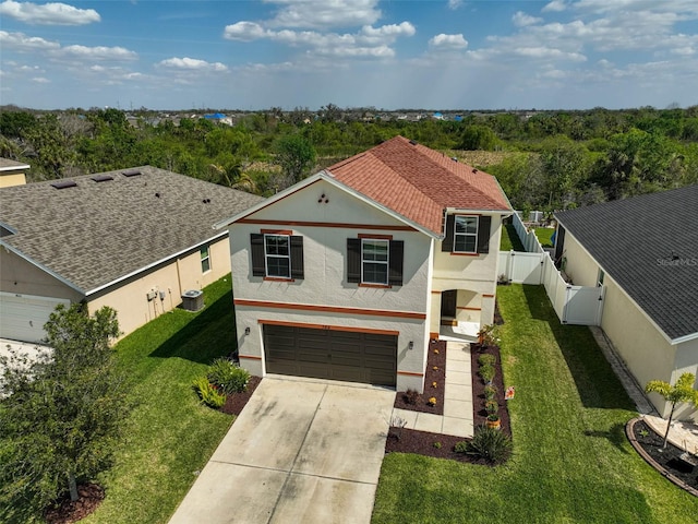 traditional home with a garage, concrete driveway, fence, a front lawn, and stucco siding