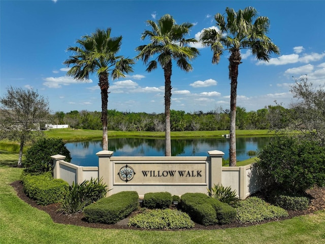 community sign featuring a water view and fence