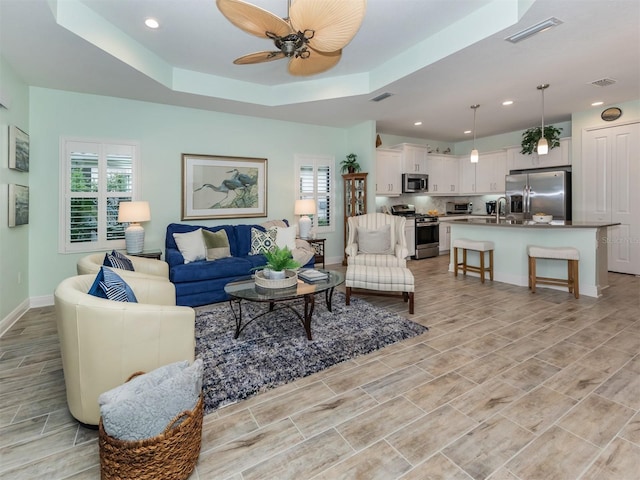 living area featuring a wealth of natural light, visible vents, and a tray ceiling