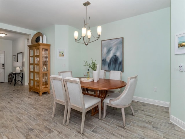 dining area with baseboards, a notable chandelier, and wood tiled floor