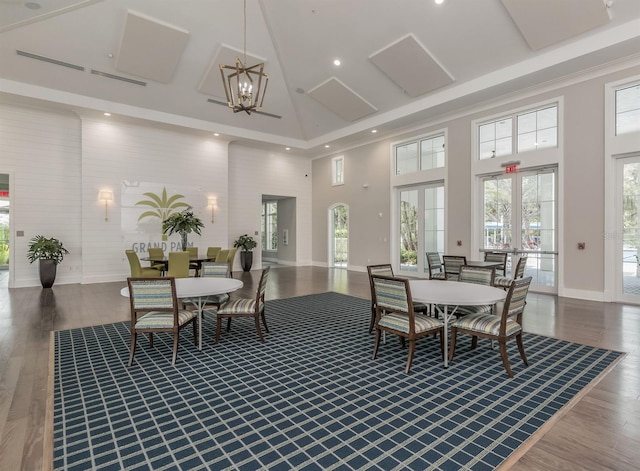 dining room featuring wood finished floors, recessed lighting, a high ceiling, an inviting chandelier, and baseboards