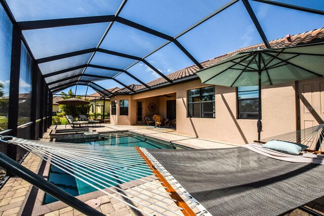 view of pool featuring a lanai, a pool with connected hot tub, ceiling fan, and a patio area