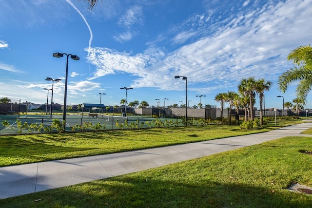 surrounding community with a yard, a tennis court, and fence