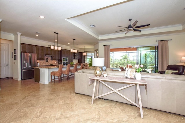 living room with a raised ceiling, crown molding, recessed lighting, and a ceiling fan