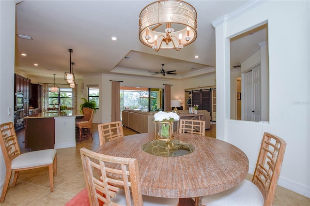 dining room with a tray ceiling, light tile patterned flooring, ceiling fan, ornamental molding, and a barn door