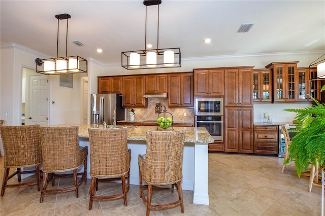 kitchen with a large island, visible vents, brown cabinets, and stainless steel appliances