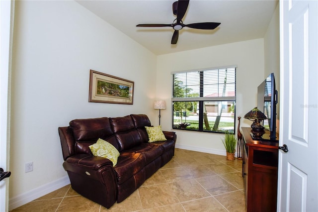 living area with light tile patterned floors, a ceiling fan, and baseboards