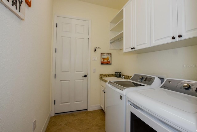 clothes washing area featuring a sink, cabinet space, separate washer and dryer, light tile patterned floors, and baseboards