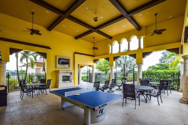 view of patio / terrace featuring outdoor dining area, fence, ceiling fan, and a tile fireplace