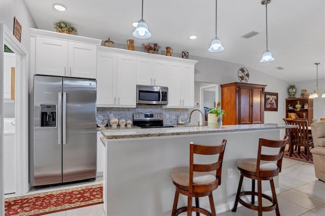 kitchen featuring visible vents, decorative backsplash, lofted ceiling, appliances with stainless steel finishes, and white cabinetry