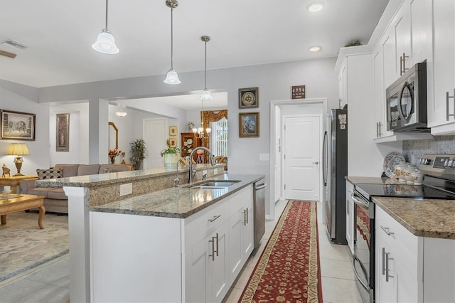 kitchen featuring a center island with sink, visible vents, appliances with stainless steel finishes, white cabinetry, and a sink