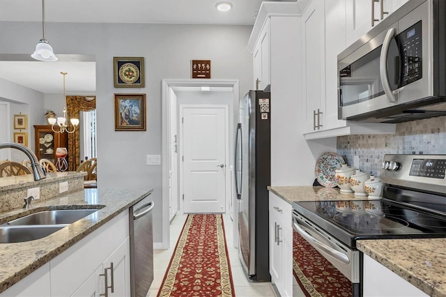 kitchen featuring a notable chandelier, stainless steel appliances, tasteful backsplash, white cabinets, and a sink