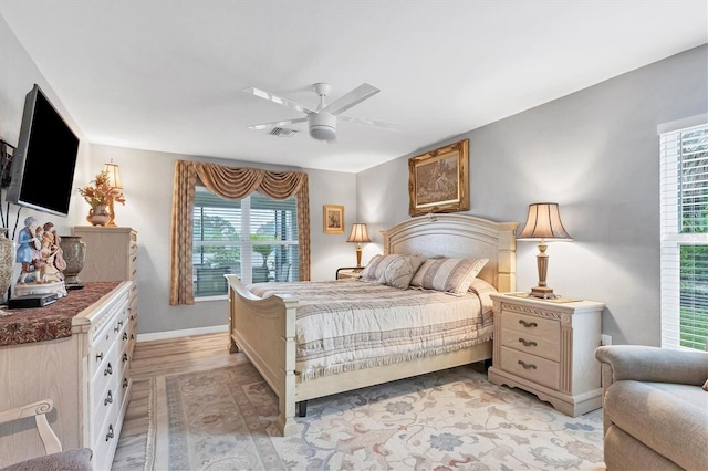 bedroom featuring light wood finished floors, ceiling fan, visible vents, and baseboards