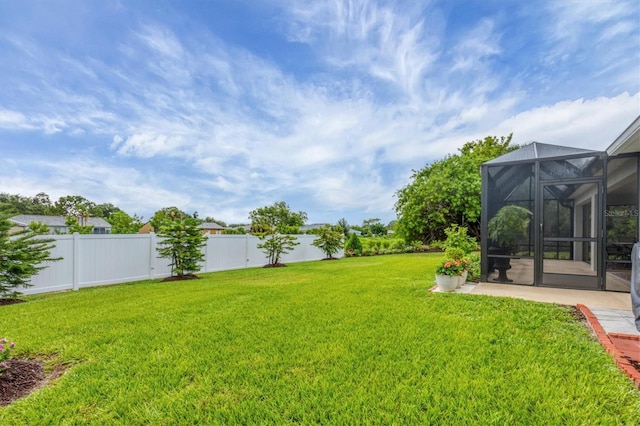 view of yard featuring a lanai, a patio area, and fence