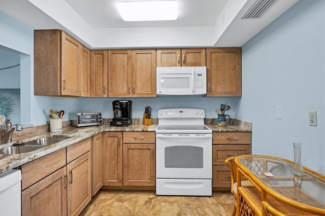 kitchen with white appliances, a sink, visible vents, brown cabinets, and light stone countertops