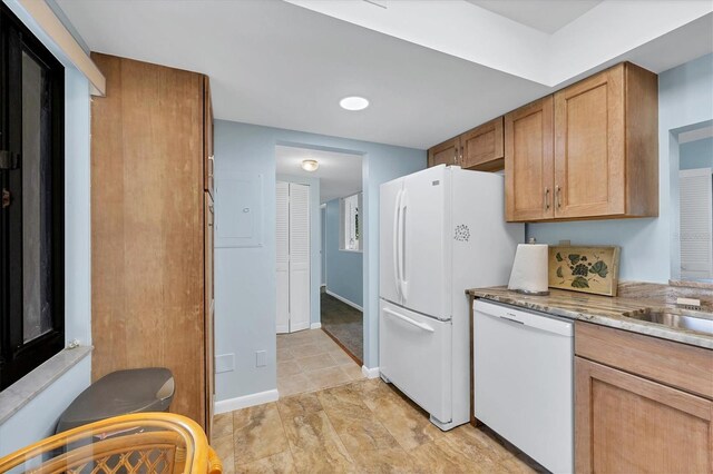 kitchen featuring white appliances, brown cabinetry, and baseboards