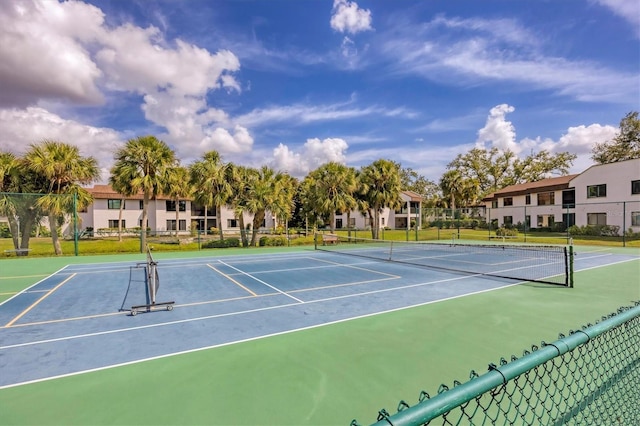 view of tennis court featuring a residential view and fence