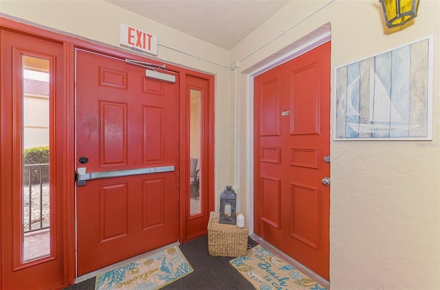 entrance foyer featuring dark colored carpet, a textured wall, and a textured ceiling