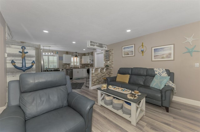 living area featuring light wood-style flooring, baseboards, and recessed lighting