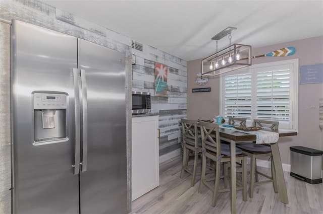 kitchen with baseboards, visible vents, light wood-style flooring, an accent wall, and stainless steel appliances