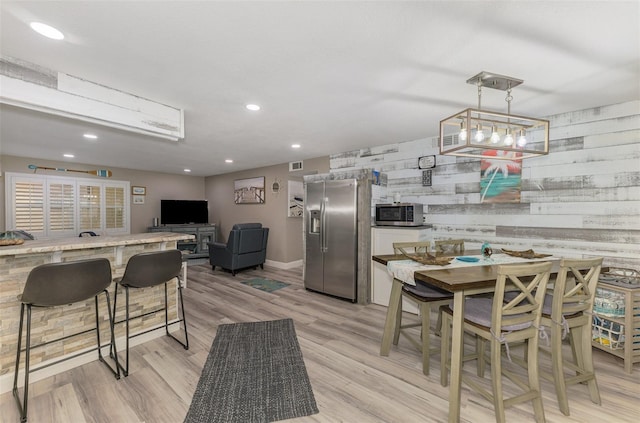 kitchen featuring recessed lighting, visible vents, appliances with stainless steel finishes, wood walls, and light wood-type flooring