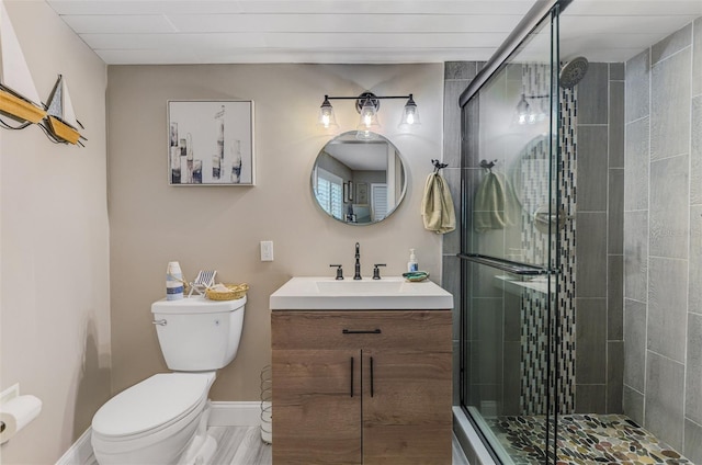 bathroom with baseboards, toilet, a shower stall, and vanity