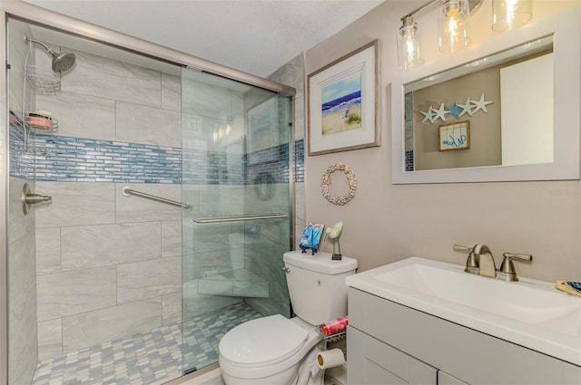 full bathroom featuring toilet, a shower stall, a textured ceiling, and vanity