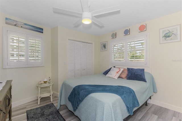 bedroom with ceiling fan, a closet, light wood-type flooring, and baseboards