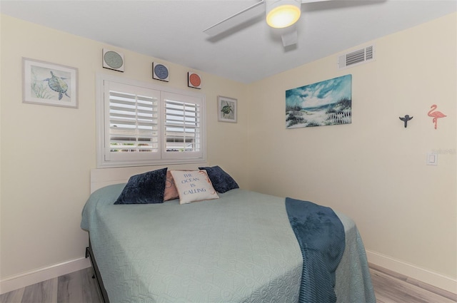 bedroom with baseboards, visible vents, and wood finished floors