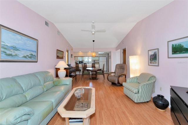 living room featuring lofted ceiling, light wood-type flooring, and visible vents