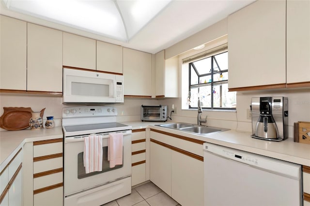 kitchen featuring light tile patterned floors, cream cabinets, white appliances, a sink, and light countertops