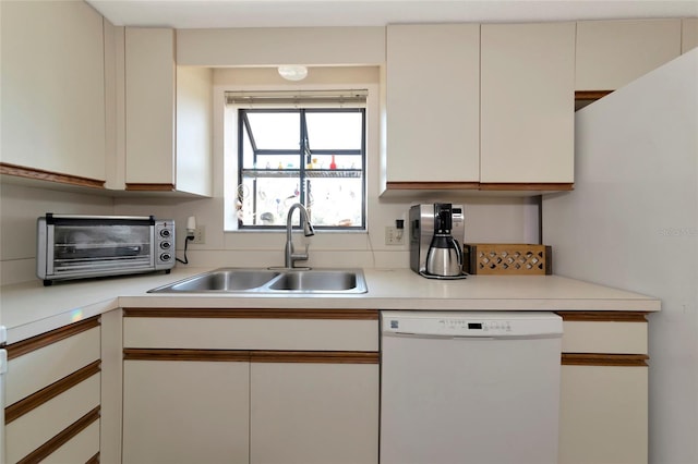 kitchen with a toaster, light countertops, white dishwasher, and a sink