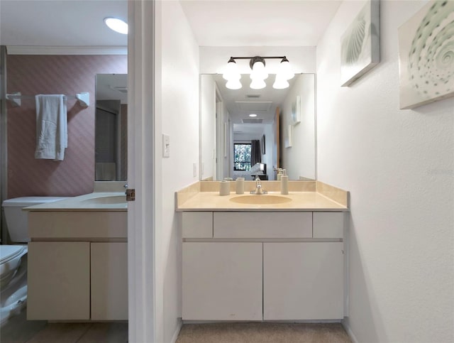 bathroom featuring two vanities, a sink, toilet, and wallpapered walls