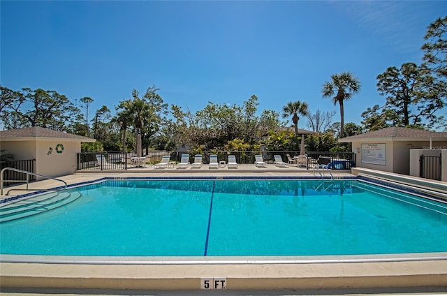 community pool with a patio and fence