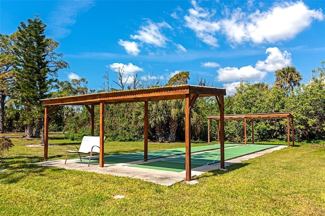 view of property's community with shuffleboard and a yard