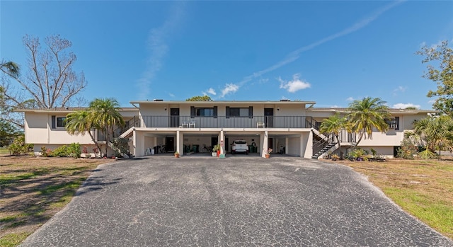 view of front of property with stairs, a carport, and aphalt driveway