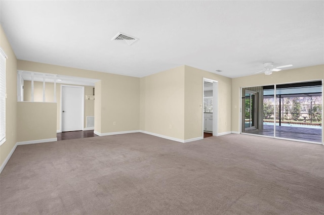 carpeted spare room with baseboards, ceiling fan, and visible vents