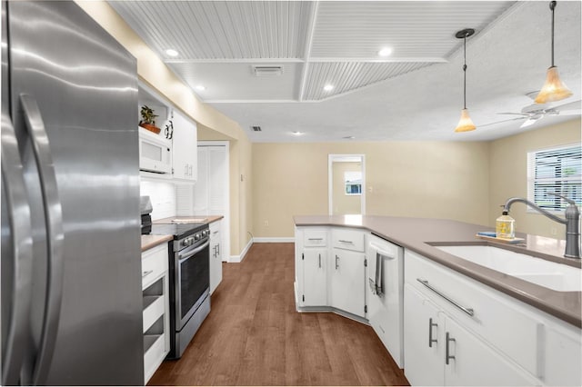 kitchen with dark wood finished floors, ceiling fan, a sink, stainless steel appliances, and white cabinets