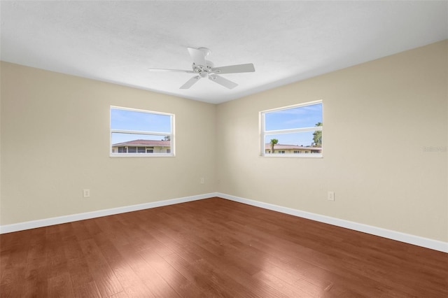 empty room featuring ceiling fan, a wealth of natural light, baseboards, and wood finished floors