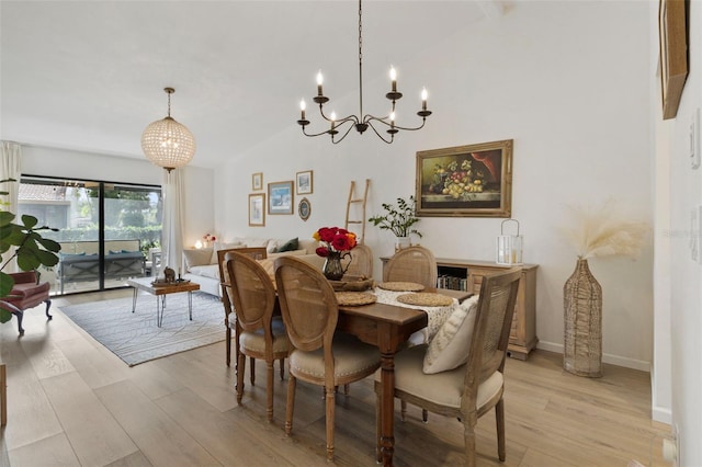 dining room with light wood-style floors, a notable chandelier, high vaulted ceiling, and baseboards