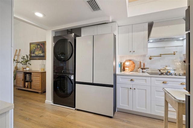 clothes washing area featuring stacked washer and dryer, recessed lighting, visible vents, and light wood finished floors