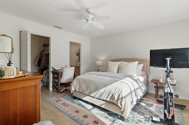 bedroom with visible vents, a ceiling fan, a spacious closet, a closet, and light wood finished floors