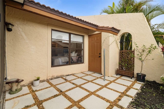 doorway to property with a tiled roof and stucco siding